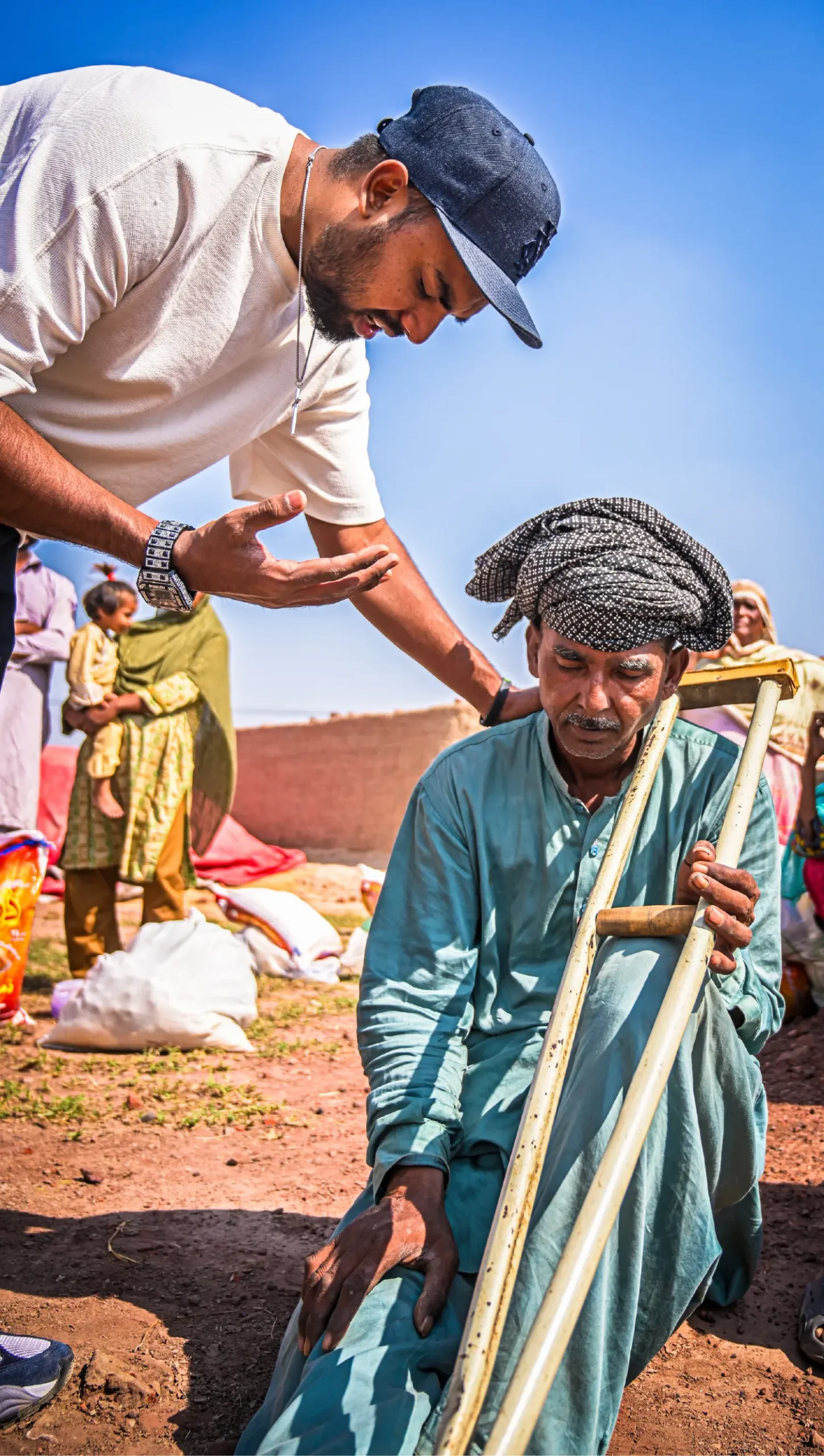 Pastor Suryani Javed praying over a man with crutches who came to receive his ration