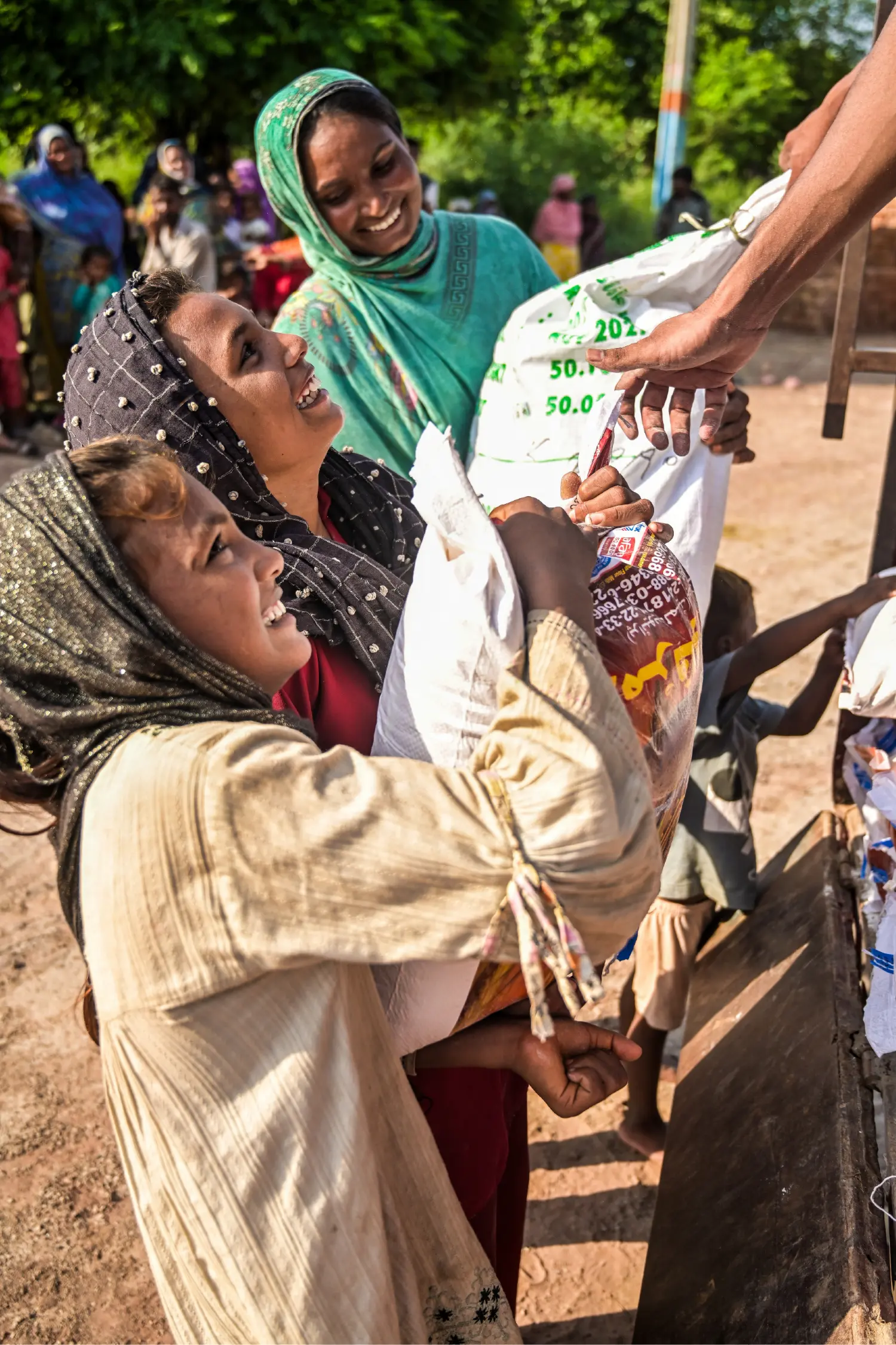 A little girl sitting beside her family's food ration, smiling with joy