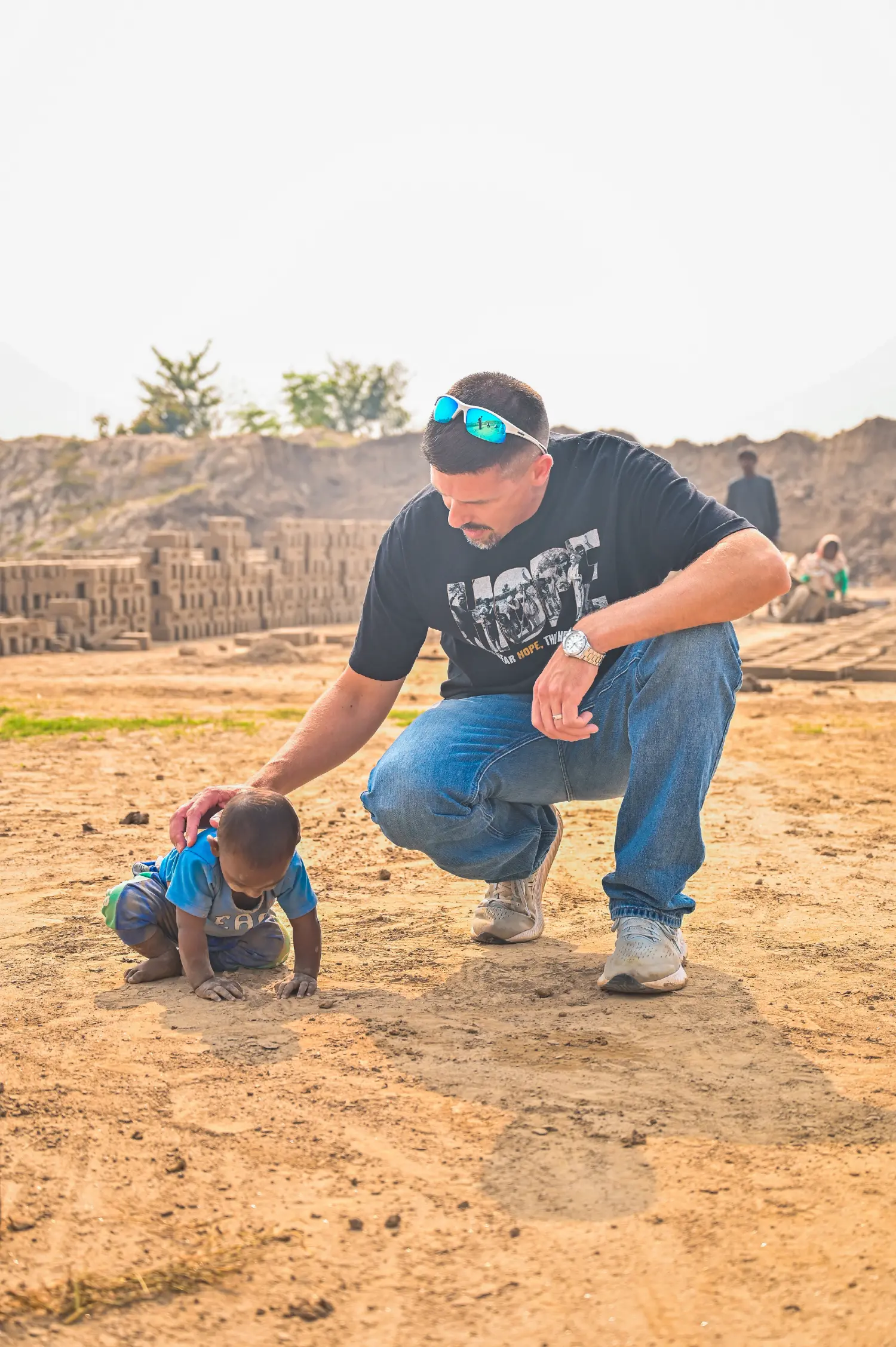 A pastor from the United States looking at a young child working in the mud