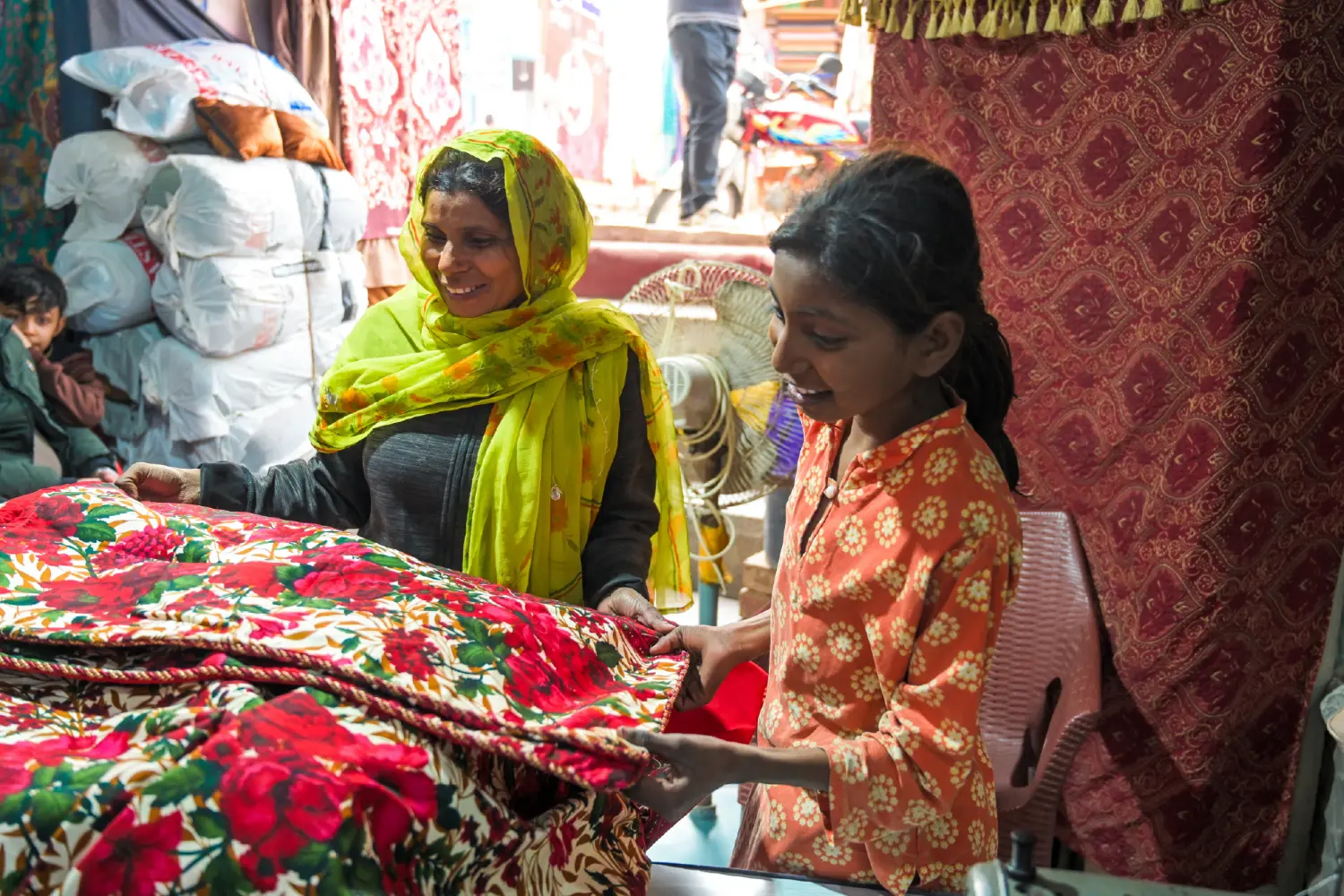 A woman and her daughter purchasing bed sheets and laughing