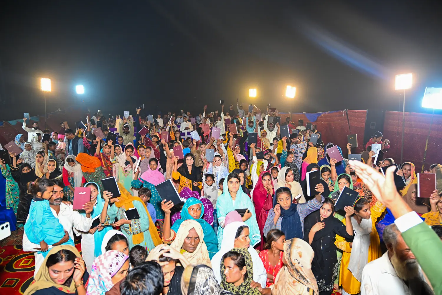 A crowd raising the Holy Bibles they have received from H.O.P.E.