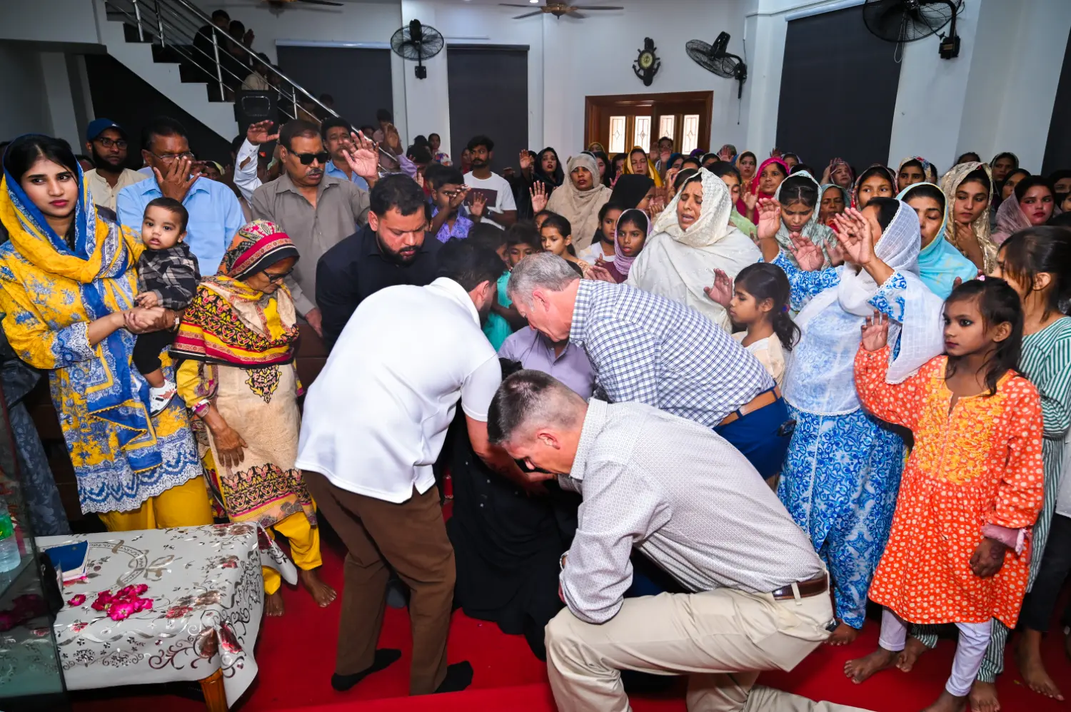 Pastors from Pakistan and the United States praying over a man at New Hope Church
