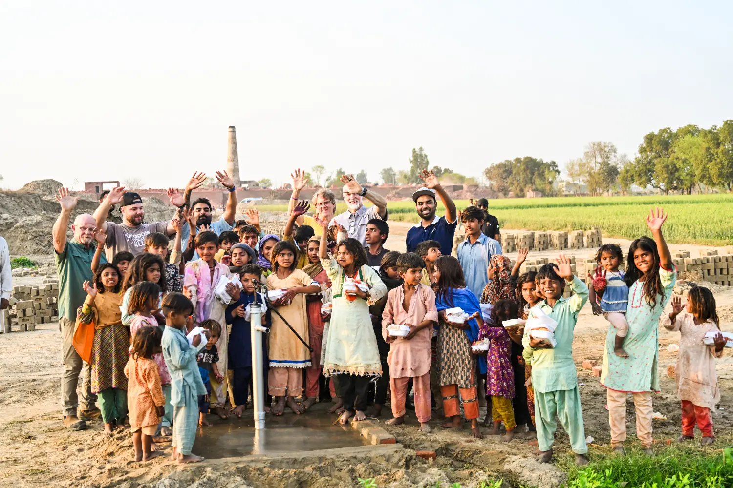 Pastor Mark, Brother Jordan, Pastor Shawn and Pastor Suryani Javed with children, food and a clean water pump at the brick kiln