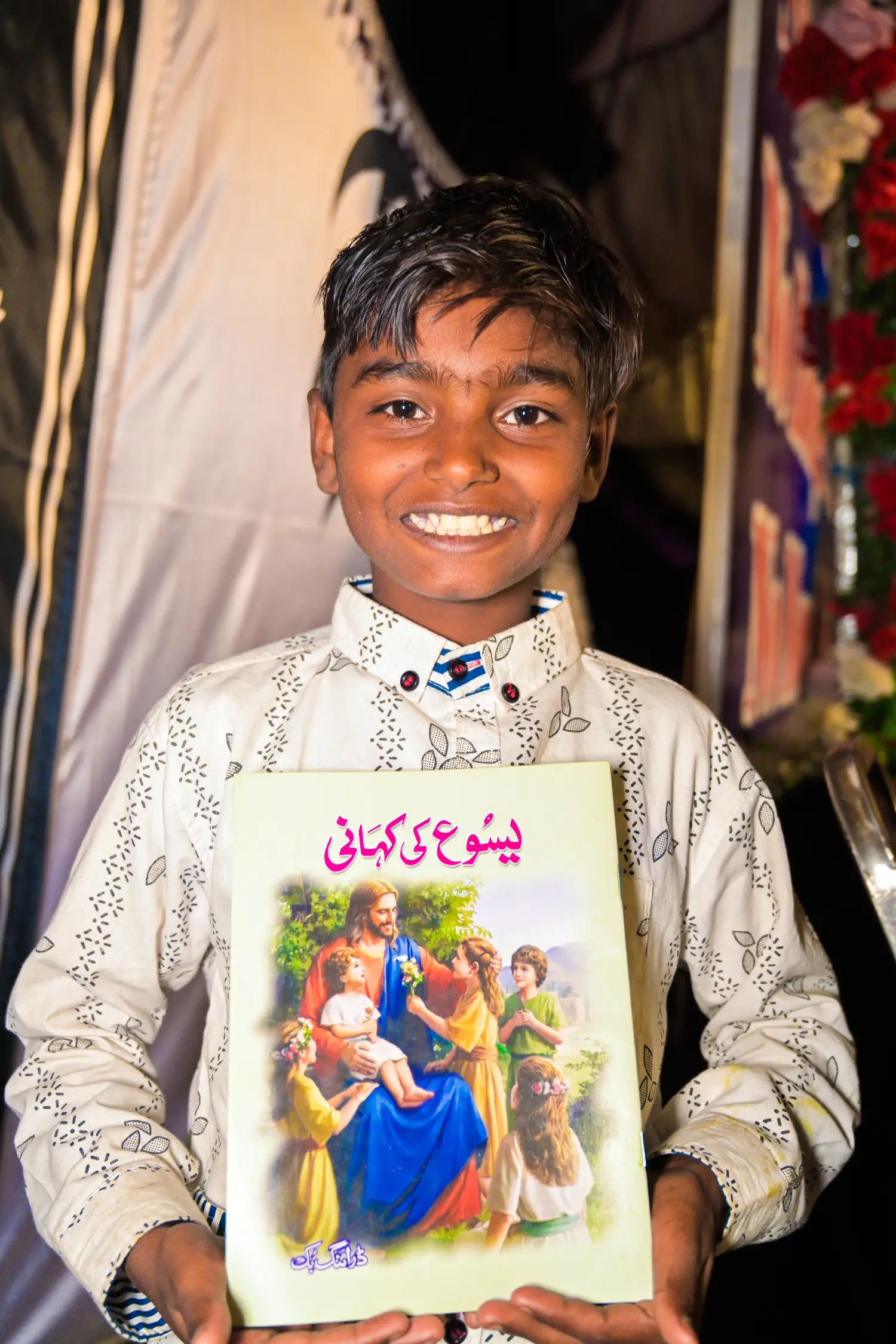 A young boy smiling, holding a children's Bible