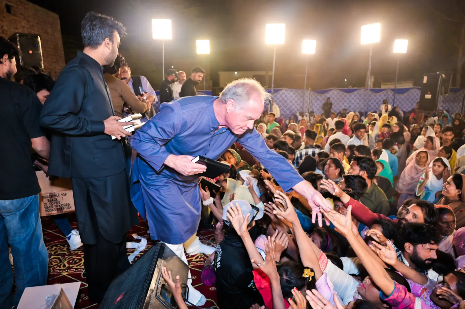 Mr. Roger King handing out Holy Bibles to a crowd of people