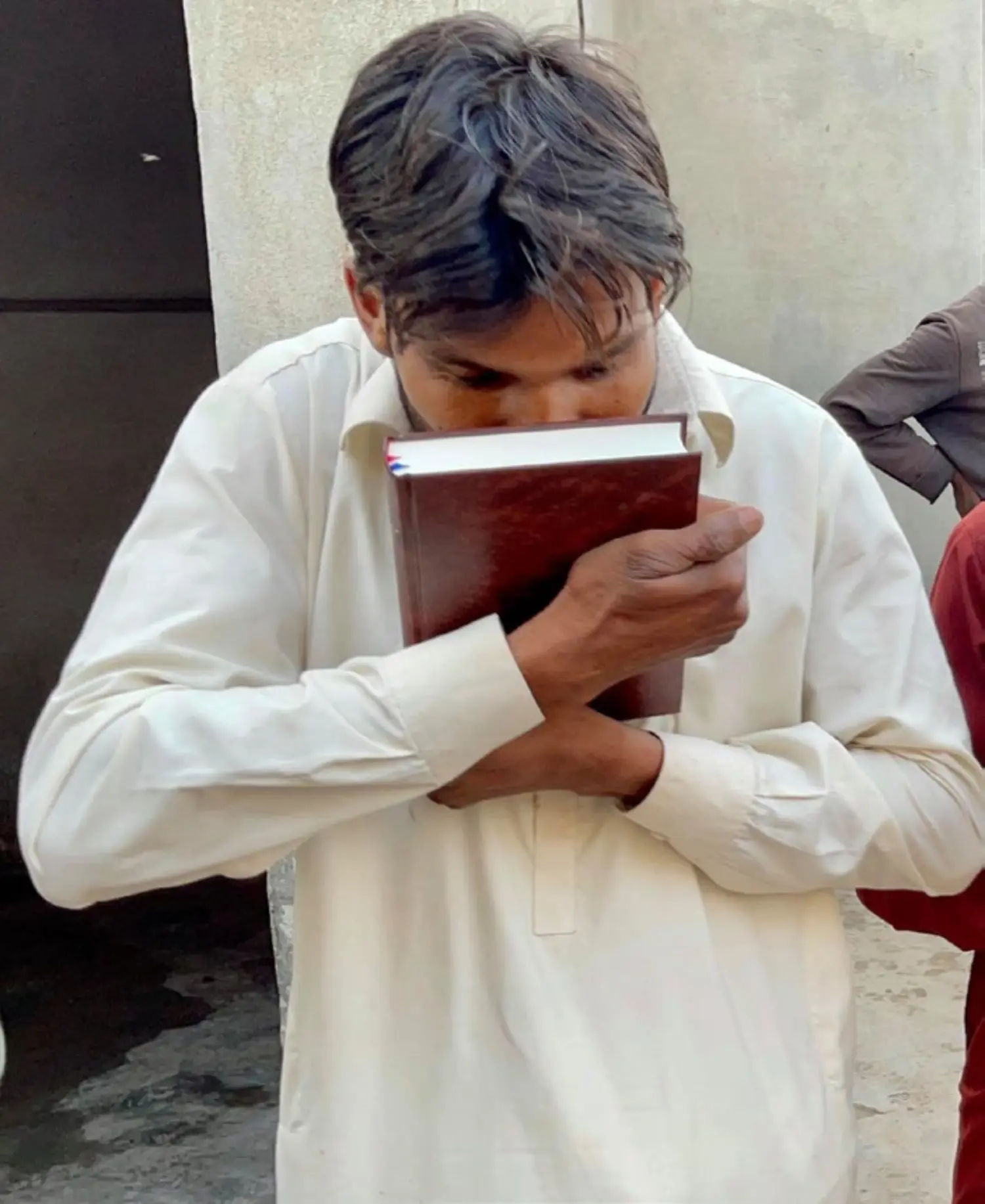 A man kissing the Holy Bible he has received
